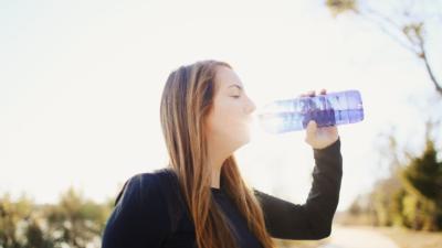 woman drinking from a water bottle during outdoor exercise